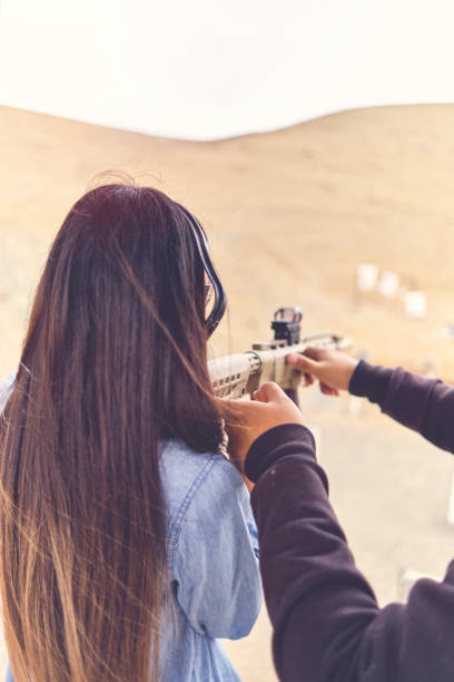 mujer liberando estrés, instructor ayudando a la mujer con arma - shooting women gun shotgun fotografías e imágenes de stock