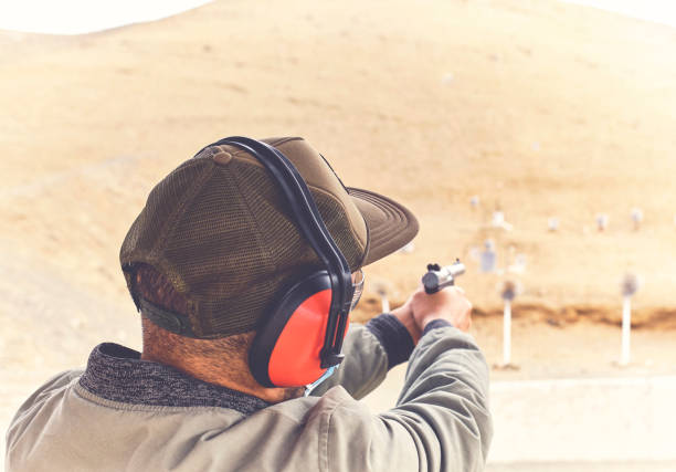 Man with hand gun aiming at shooting range and releasing stress, post pandemic concept