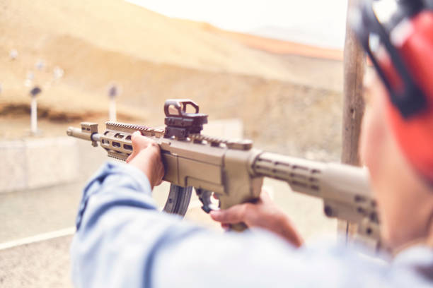 istock Woman empowered shooter aiming assault rifle at target. Selective Focus 1335443352