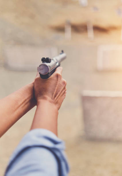 pistola en manos de una niña, brazos de cerca. - shooting women gun shotgun fotografías e imágenes de stock