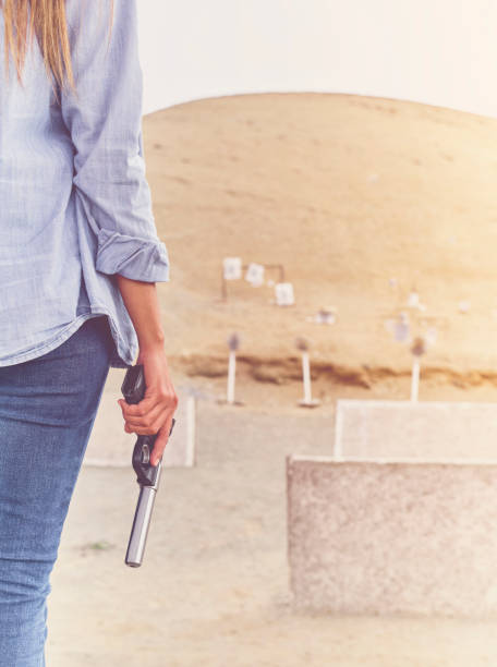 pistola en manos de una niña, brazos de cerca. - shooting women gun shotgun fotografías e imágenes de stock