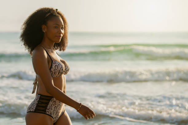 istock Afro woman enjoying the sunset while walking along the beach. 1335445156