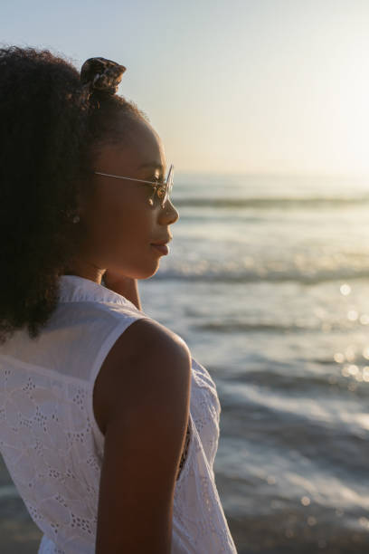 istock Young woman relaxing while enjoying the sunset at the beach. 1335445209