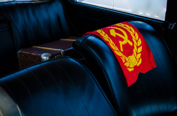 The famous hammer and sickle emblem of the Soviet Union flag is draped over the leather car seat of a vintage car.