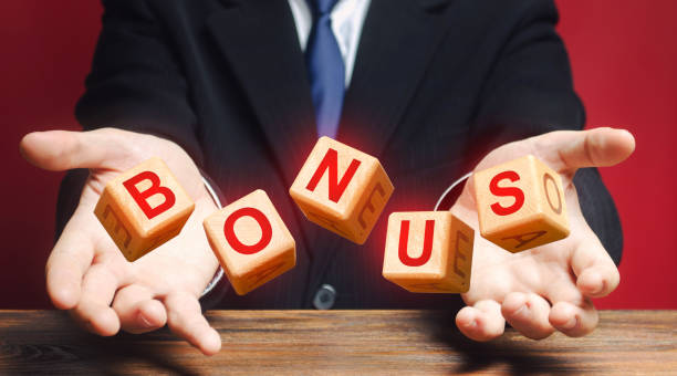 istock Cubes thrown by a man make word BONUS. Receive bonuses, rewards and preferences. A nice addition. Salary increase, wage premium for holidays. Favorable purchase and special promotions. Rising at work. 1335446362