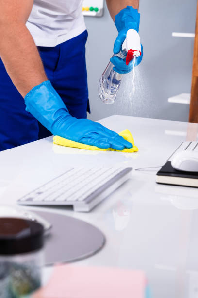 istock Janitor cleaning white desk in office 1335446650