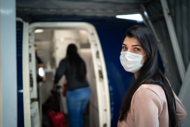portrait of young traveller woman wearing face mask on airplane - entering airplane imagens e fotografias de stock