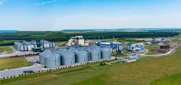 istock Modern plant with grain elevators on field. Granary for keeping agricultural products. Silver bins for storing crop. Aerial view 1335457309
