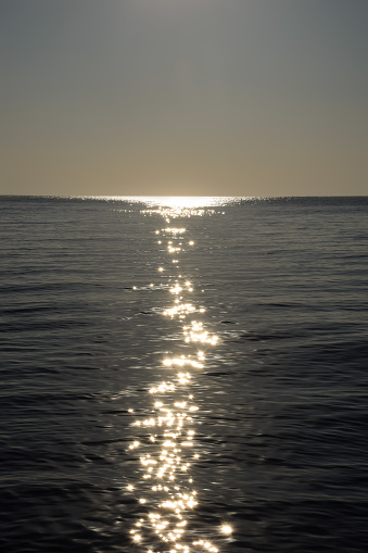 The bright reflection of the moon to the very horizon on the calm sea waves in the late evening. The moon and sun itself is not visible
