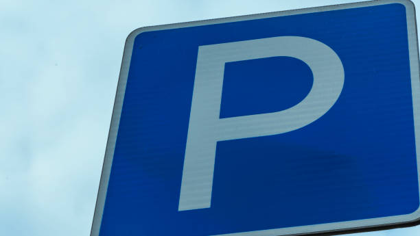istock Blue road sign with letter P on rectangular plate isolated against a blue sky. Parking symbol on a cloudy blue sky background. Space for text. 1335470690