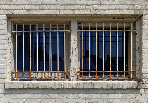 Weathered building window with rusty security bars.