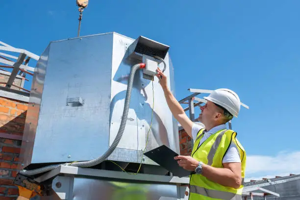 Photo of Engineer with clipboard checking the installation of the ventilation system