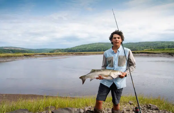 A beautiful 30" striped bass caught in a tidal river by a teen fisherman