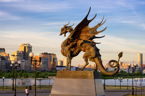 Kazan, Russia - June 18, 2021: Statue of Dragon Zilant at Wedding palace (Family center) in Kazan, Tatarstan. This place is tourist attraction of city. Kazan cityscape at sunset. Travel concept.