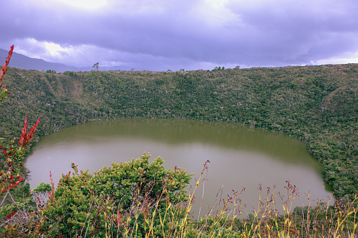 Colombia, Laguna de Guatavita - This is the lake that the colonial Spanish and others tried to drain in search of gold that was said to have been thrown into the lake during various religious ceremonies of the Muisca people. In spite of cutting a wedge into one side of the surrounding mountains, they only managed to lower the level of the lake a little bit. They found a few artifacts on the lake shores. This is the origin of the original legend of El Dorado. The lake continues to be sacred to the Muiscas. The depth of the lake is 125 metres. Image shot from an altitide of 3,100 metres above mean sea level, on the Andes Mountains, on an overcast morning during steady and continous rain.