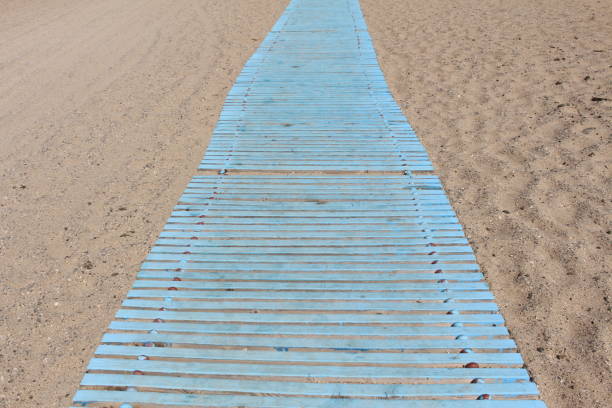istock Blue colored wooden path on the hot sand 1335482800