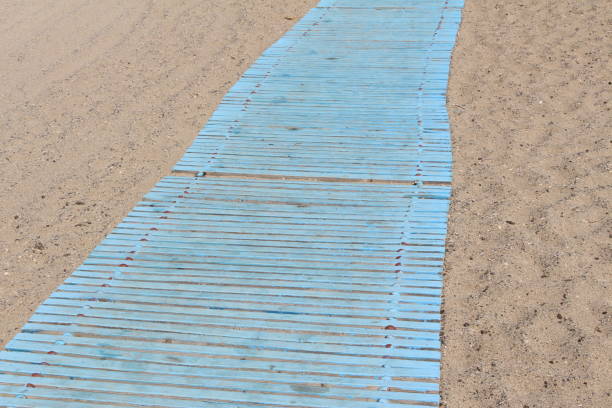 istock Blue colored wooden path on the hot sand 1335482812