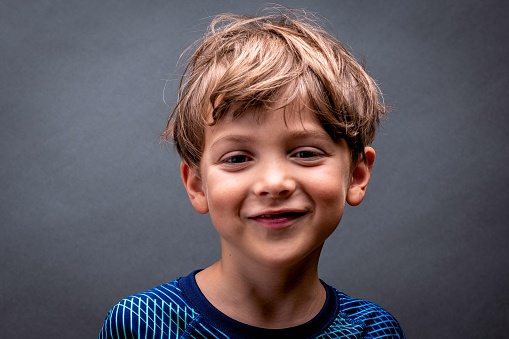 Smiling caucasian little boy looking at the camera on gray background