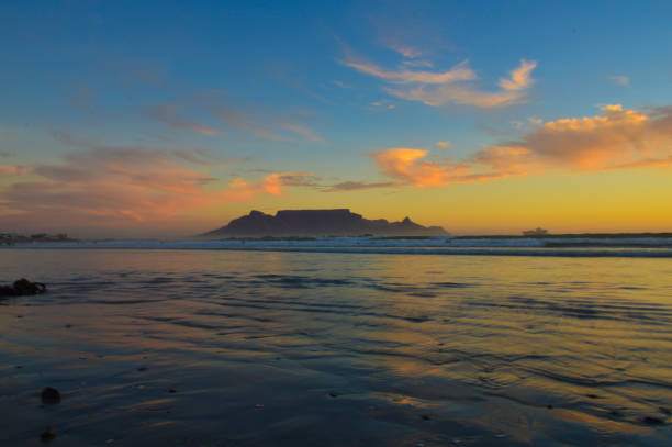 céu dramático na praia do pôr do sol em bloubergstrand cidade do cabo com montanha de mesa na queda traseira - south africa coastline sea wave - fotografias e filmes do acervo