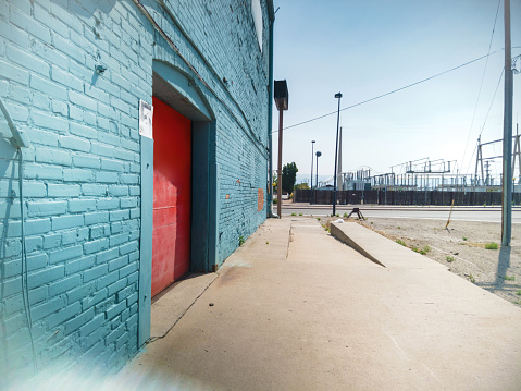 In Western Colorado Loading Dock with Blue Brick Wall and Red Garage Door Urban City Photo Series (Shot with DJI Pocket 2 Cam 9216  ×  6912 at 64mp photos professionally retouched - Lightroom / Photoshop - downsampled as needed for clarity and select focus used for dramatic effect)