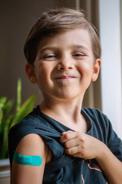 sześcioletnie dziecko pokazujące swoją opaskę tuż po szczepieniu - children only healthy lifestyle vertical close up zdjęcia i obrazy z banku zdjęć