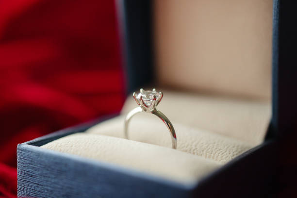 istock Diamond ring in jewelry gift box on red fabric background 1335499715