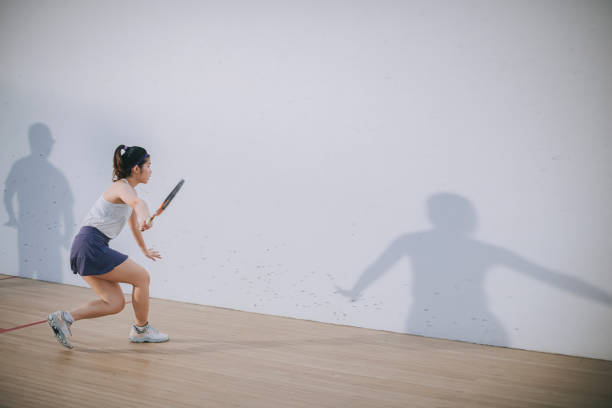 Asian squash coach father guiding teaching his daughter squash sport practicing together in squash court