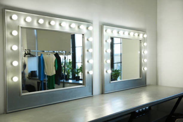 istock Two mirrors with illuminated lights behind the scenes, with a reflection of a hanger with clothes 1335521271