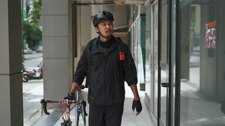 Asian delivery man walking  and towing bicycle