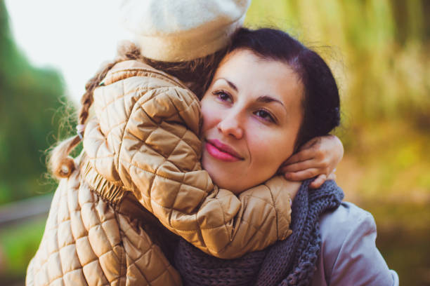 istock girl in a mustard-colored jacket hugs her mother 1335529528