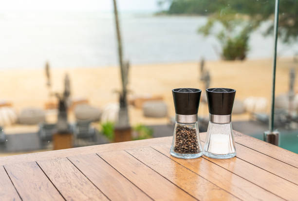Salt and peppercorn grinder bottles on cafe table near beach