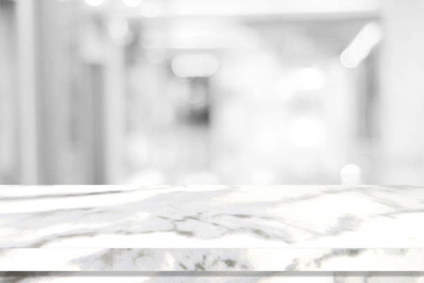 istock Empty white table top, counter, desk over blur perspective store with bokeh light background, White marble stone table, shelf and blurred shop for food, product display mockup, template backdrop, banner, Retail business wallpaper, poster 1335532523