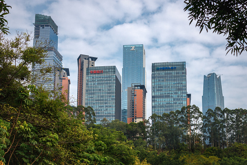 The contrast between a tranquil park (Shimen Forest Park, 石门森林公园) and the towering cluster of buildings in ASEAN Business District in Nanning, Guangxi Zhuang Autonomous Region, China. The buildings include: Guangxi China Resources Tower, Jiuzhou International Tower, Logan Century Center, etc.