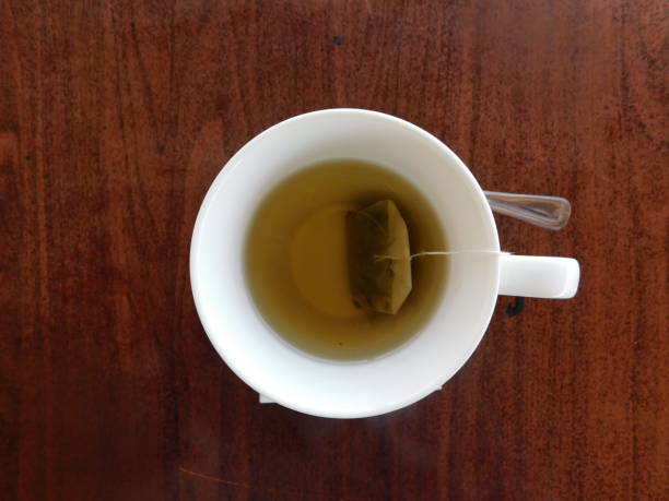istock green tea in a white cup on a wooden table. 1335535173
