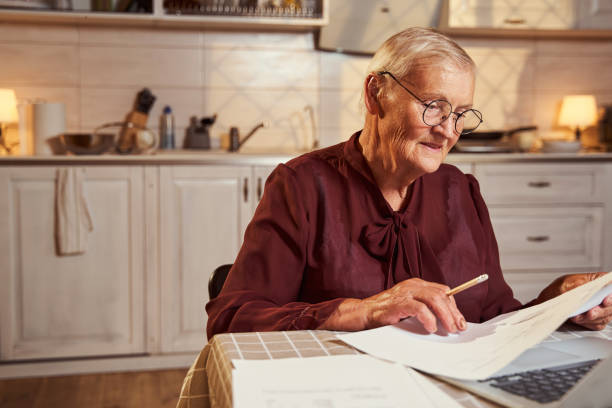 istock Senior person reading business reports at home during remote work 1335538139