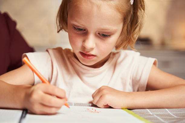 istock Concentrated kid using orange marker for painting picture 1335538223