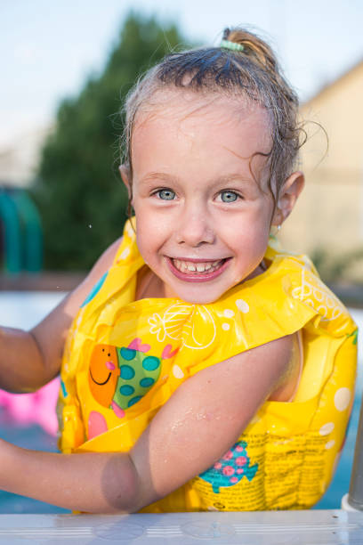 Young mother, swimming instructor and happy little boy in paddling pool. Teaches infant child to swim. Enjoy first day of swimming in water. Mom holds child preparing for diving. doing exercises