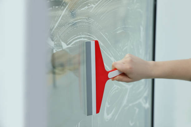 istock Woman cleaning window with squeegee indoors, closeup 1335545516