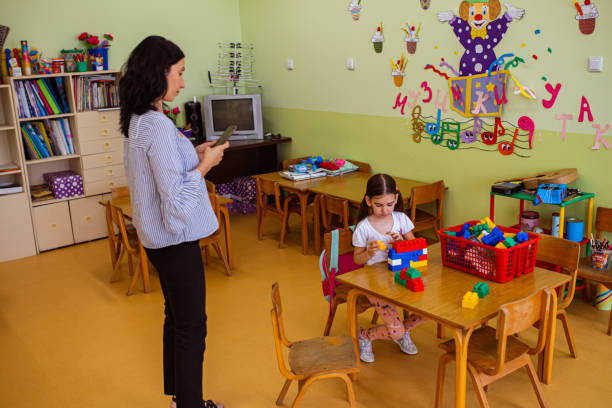 istock Preschool teacher taking photo of her creative student while she making a structure with colorful toy blocks 1335545662