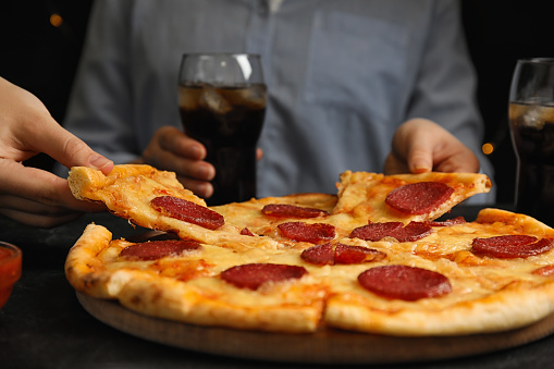 Women taking tasty pepperoni pizza at table, closeup