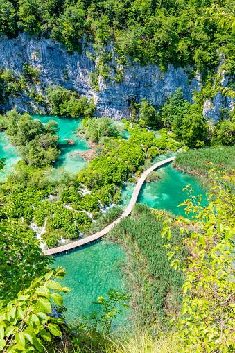 Aerial view of wooden footpath trail at Plitvice lakes, Croatia. Tourist path above blue lagoon near the waterfalls. Empty bridge without peoples.