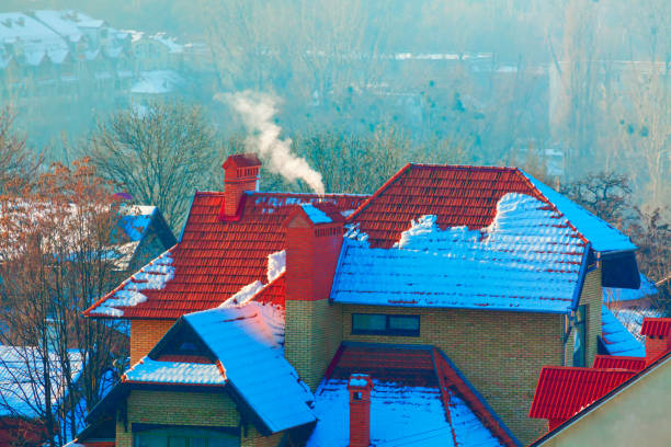 Snow-covered surface for product placement. Blurred house made of wood and stone on background. Snowfall on winter day. Christmas background with wooden cottage or chalet at ski resort. Copyspace for design.