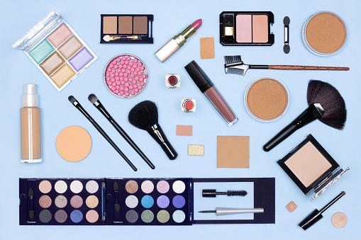 Make-up flat lay. Various makeup products and accessories on blue table, top view