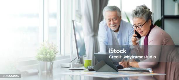 Old Senior Asian Retired People Entrepreneur Working Together At Home Home Isolation Remote Jobs Work With Desktop And Smartphone Technology Device Work From Home Stock Photo - Download Image Now