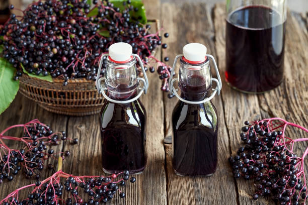 istock Two bottles of black elder syrup with fresh elderberries 1335561691