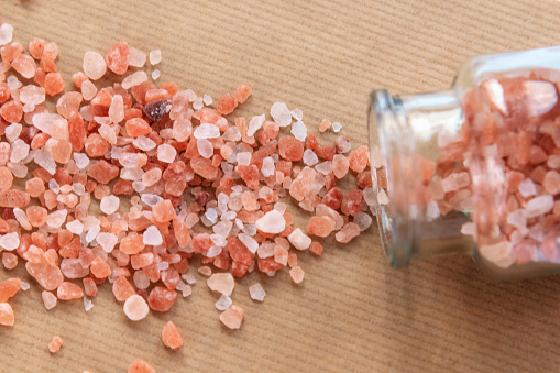 Himalayan pink salt scattered from glass bottle, top view. Close up.