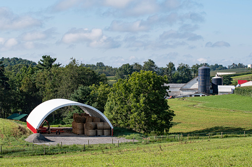 Traditional farm buildings in the background with a modern hoop barn in the foreground in rural Appalachia.