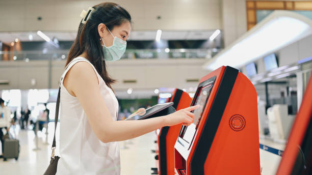 istock Asian thai / taiwanese with facemask cheerful Smile thai asian passenger using digital tablet using self check-in print boarding pass from automatic machine at asia airport 1335580662