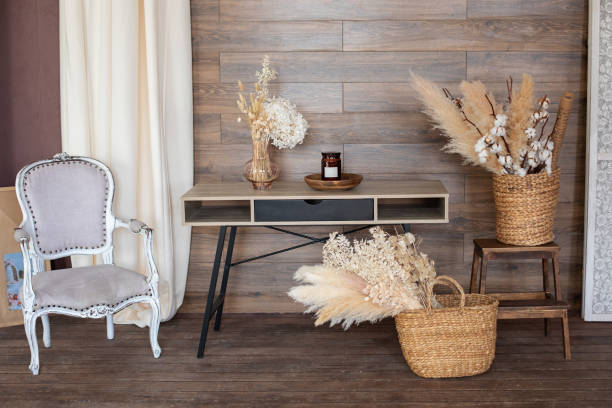 Scandinavian style home office interior. Work from home. Interior workspace home. Cozy design room home in brown tones: wooden table, armchair, wicker baskets with dried flowers and pampas grass. interior de la oficina en casa de estilo escandinavo. trabaja desde casa. espacio de trabajo interior de la casa. acogedora habitación de diseño en tonos marrones: mesa de madera, sillón, cestas de mimbre con flores secas y hierba de pampa.