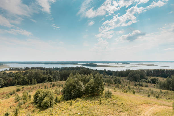 istock Summer nature landscape with sky, clouds, grass, forest trees and water lakes in the bottom. Rural scenery. Natural scene 1335600263